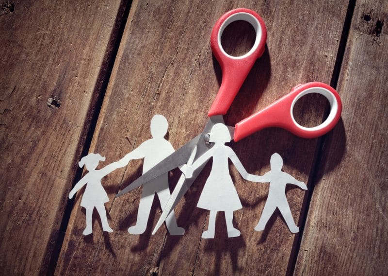 scissors cutting through a paper doll family