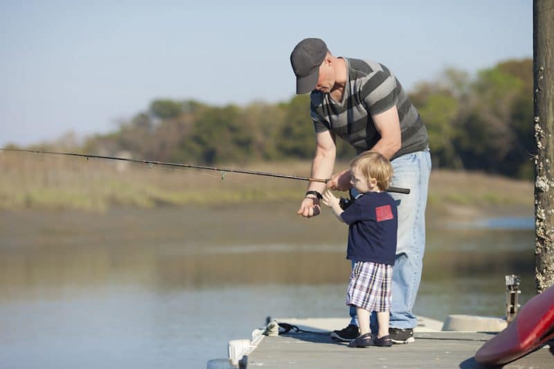 Father helping young son with a fishing pole