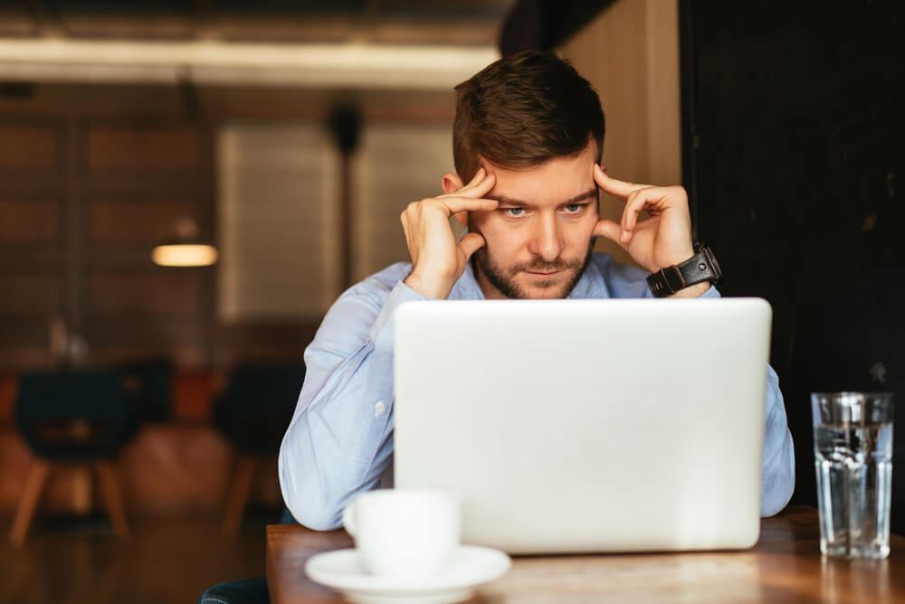 Tired man working on the laptop in a cafe.