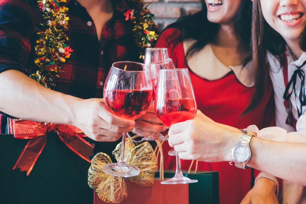 People toasting with glasses at holiday gathering.